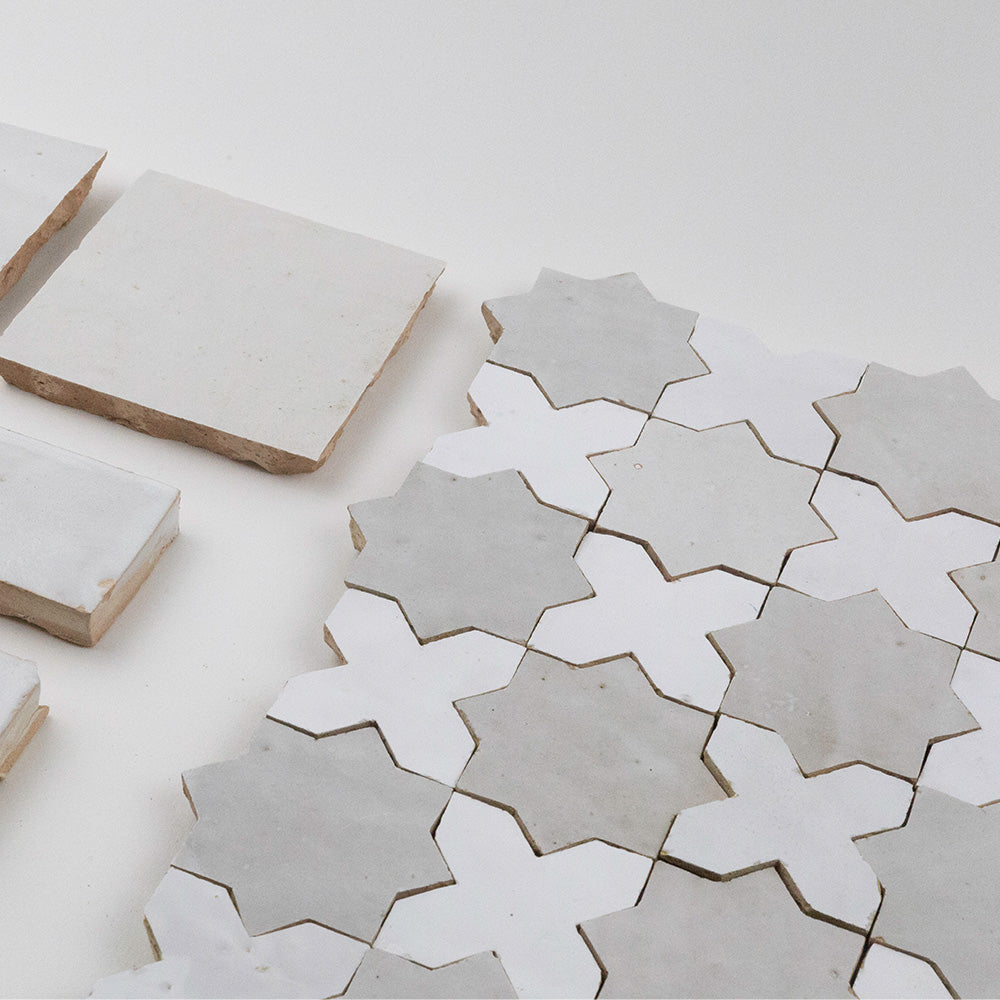 Constellation zellige mosaic (Heritage) close-up — white and soft gray star-and-cross tiles on sheet with handmade edge variation