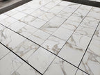 Calacatta Gold marble tile 18x18 honed, large lot layout showing white marble with soft gold and gray veining.