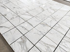 Calacatta Gold marble tile 18x18 honed, polished-look warehouse layout view showing mixed veining across multiple tiles.