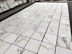 Calacatta Gold marble tile 18x18 honed, wide layout photo showing variation of gray and warm gold veining across the set.