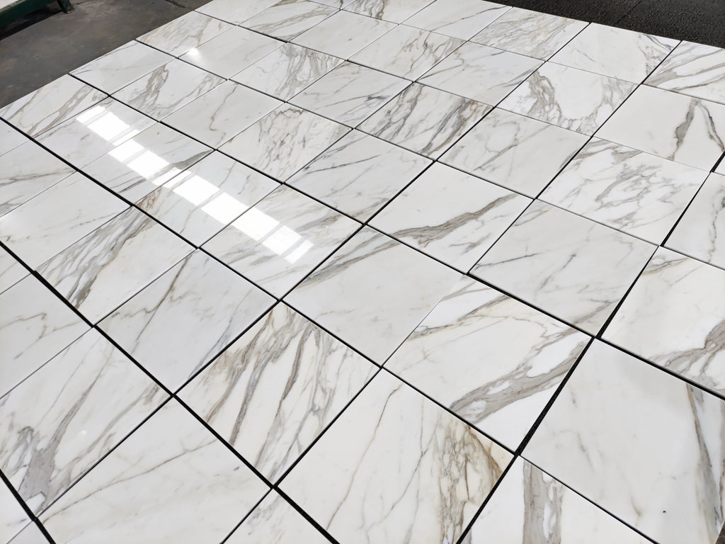 Italian Calacatta Gold marble tile 18x18 polished, dry layout showing veining variation across multiple tiles.