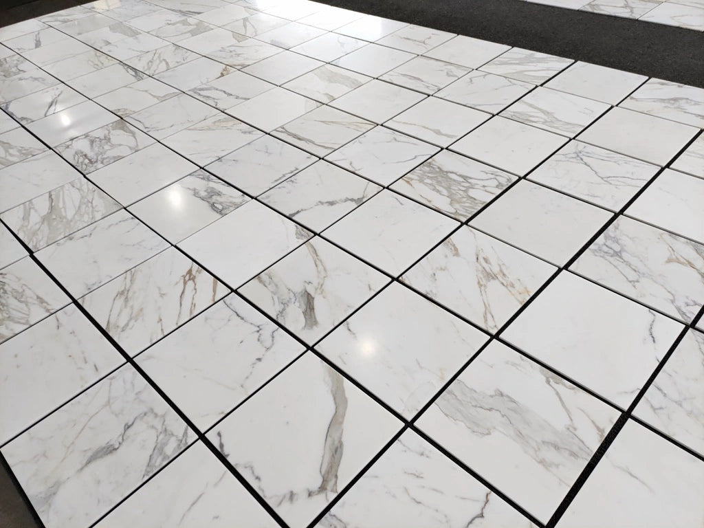 Polished 18x18 Calacatta Gold marble tile display, wide view of multiple tiles with natural vein movement.
