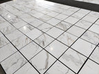 Polished 18x18 Calacatta Gold marble tile display, wide view of multiple tiles with natural vein movement.