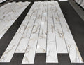 aria calacatta gold marble 12x24-patterned tiles arranged in a grid on a black floor.