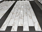 aria calacatta gold marble 12x24-patterned tiles arranged in a grid on a black floor.