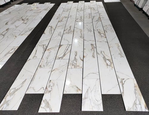 aria calacatta gold marble 12x24-patterned tiles arranged in a grid on a black floor.