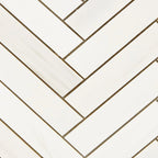 Close-up of Bianco Dolomite 1x4 herringbone marble mosaic showing tile edges, spacing, and natural stone variation.