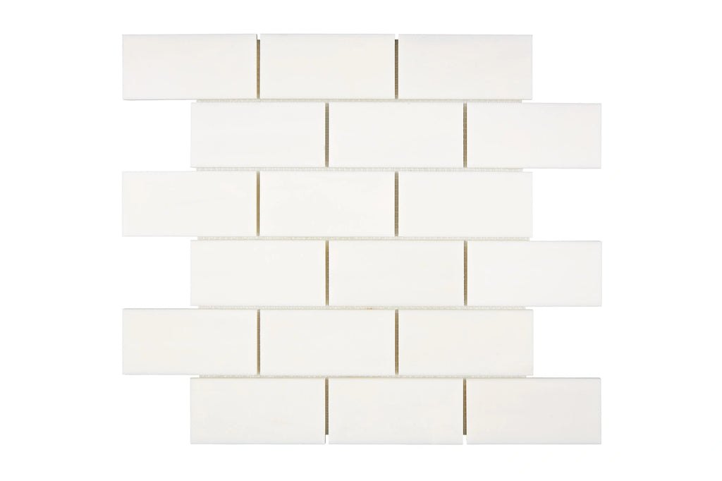 Aria Bianco Dolomite marble mosaic 2x4 brick, studio image of a mounted sheet showing subtle natural veining and soft tone variation.