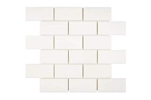 Aria Bianco Dolomite marble mosaic 2x4 brick, studio image of a mounted sheet showing subtle natural veining and soft tone variation.