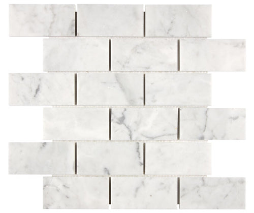 Aria Carrara White marble 2x4 brick mosaic sheet, studio image showing bright white stone with soft gray veining and natural variation across the mounted pattern.