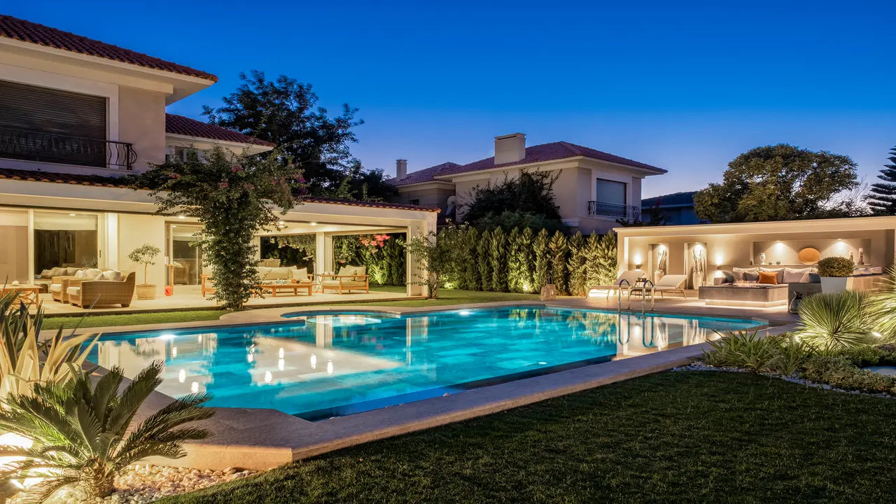 Evening view of a luxurious house with a pool and outdoor furniture.