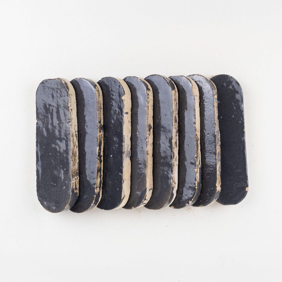 Indigo Bazaar zellige tile long oval 2x6 glossy - side view showing hand-cut edges and thickness (studio)