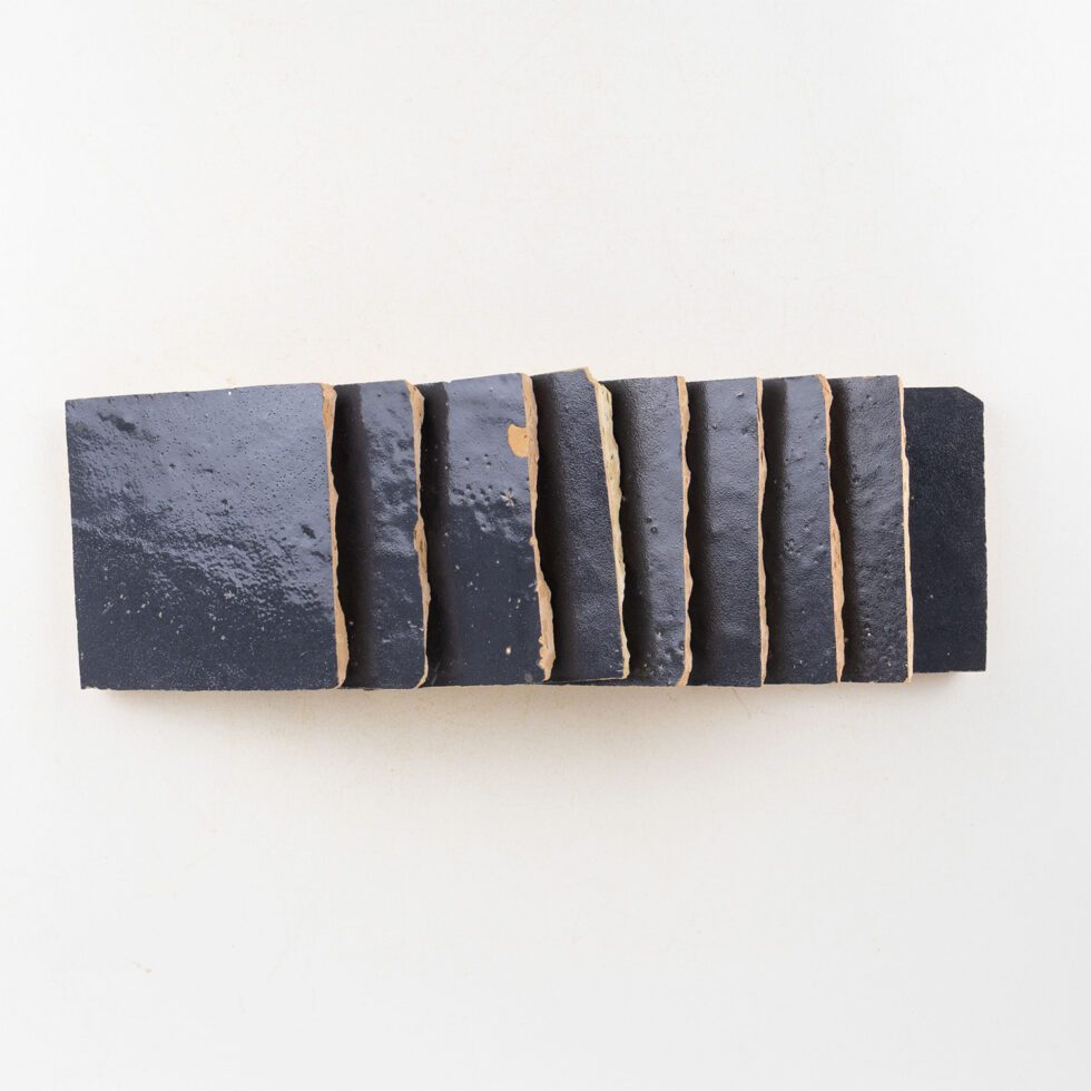 Side profile of Indigo Bazaar glossy zellige 4x4 tiles showing hand-cut edges and thickness variation.
