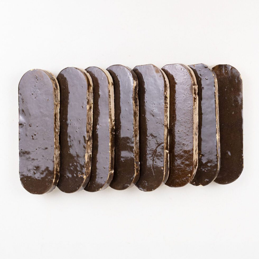 Close-up of Noir Cacao long oval zellige showing glossy glaze depth and handmade edges.