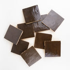 Close-up of Noir Cacao glossy zellige glaze with light-catching sheen, tonal shifts, and handmade surface texture