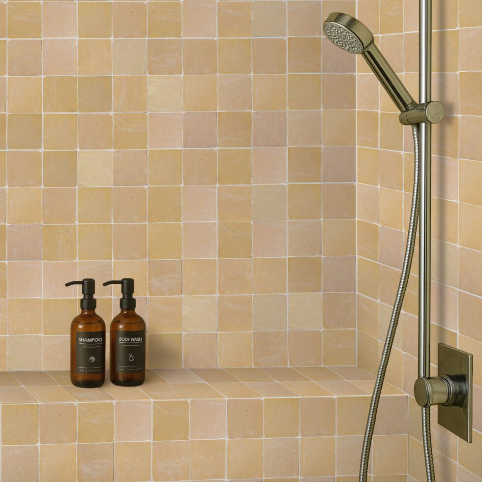 Nomad Veil zellige 4x4 tile, glossy sand-beige, installed shower wall with warm tonal variation