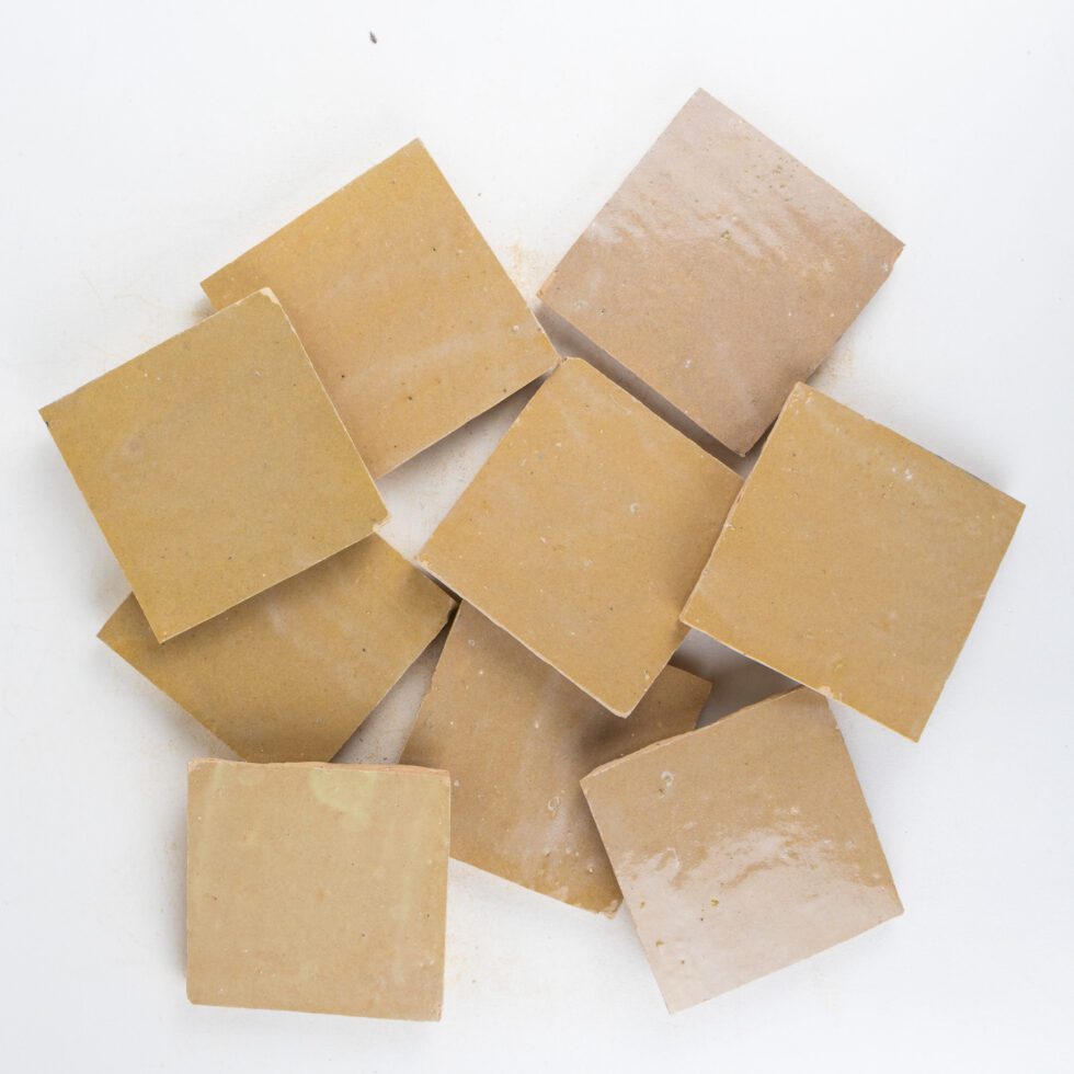 Nomad Veil zellige 4x4 tile, glossy sand-beige, loose sample tiles showing glaze movement
