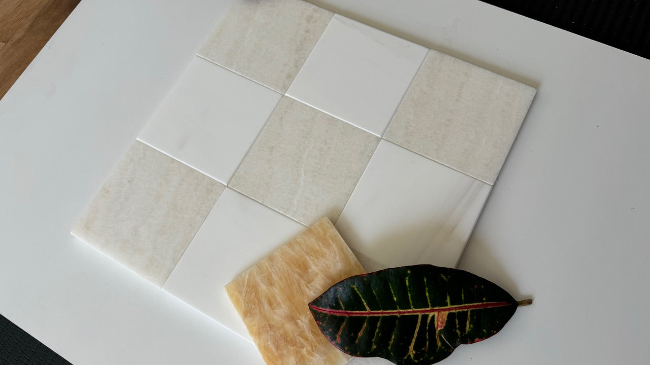 Square checkerboard onyx and marble tiles on a white surface with a leaf for scale