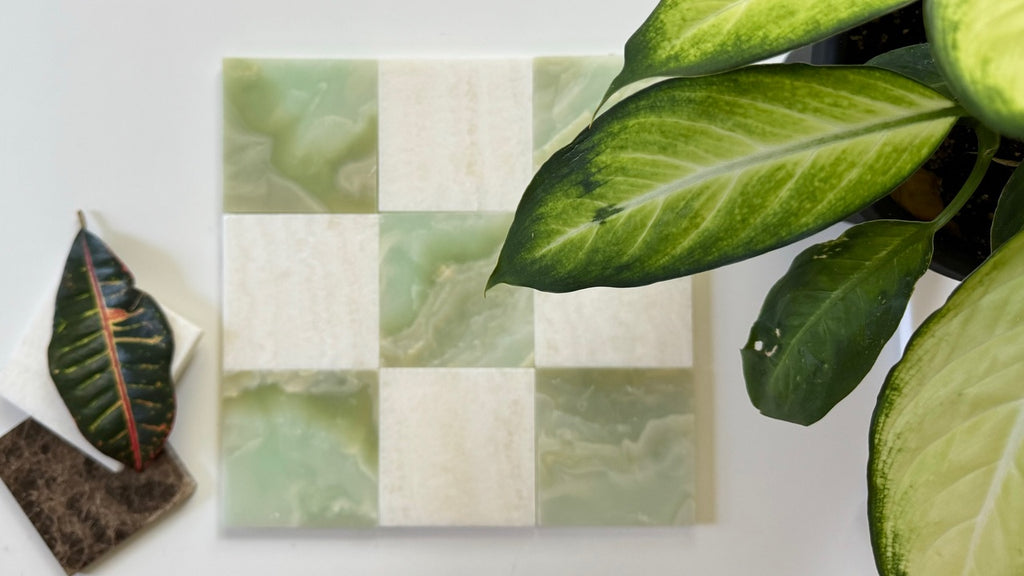 Checkered tile pattern with green and beige squares on a white surface, surrounded by leaves.