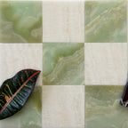 Square tiles with green and beige marble patterns and a leaf on a white background