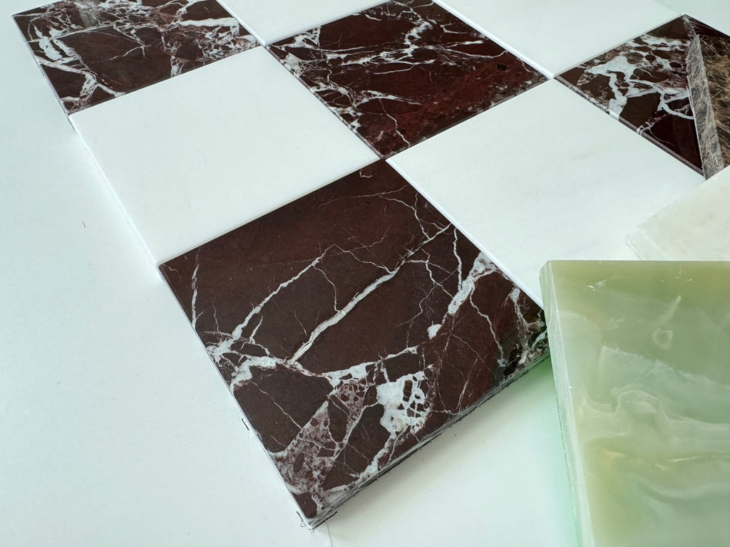 Marble-patterned tiles on a white surface with a green onyx tile