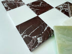 Marble-patterned tiles on a white surface with a green onyx tile