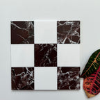 Checkered pattern of Rosso Levant and Bianco Dolomite tiles with a leaf on a light gray background